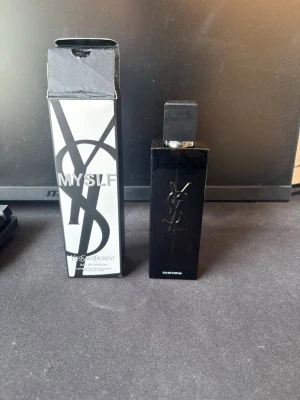 Yves Saint Laurent MYSLF Eau de Parfum - Snygg parfym från Yves Saint Laurent, MYSLF Eau de Parfum. Flaskan är svart och rektangulär med YSL-loggan i relief. Kommer i en stilren svartvit kartong med tydlig logga och text. Perfekt för dig som gillar exklusiva dofter och modern design. Jag har använt ungefär 6ml av den.