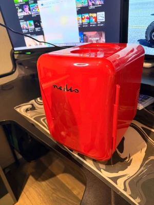 Rött sminkkylskåp från Nedis - Stilrent sminkkylskåp i blank röd plast från Nedis. Perfekt för att hålla dina skönhetsprodukter svala och fräscha. Kompakt design med rundade hörn och praktiskt handtag på ovansidan gör det enkelt att flytta runt.