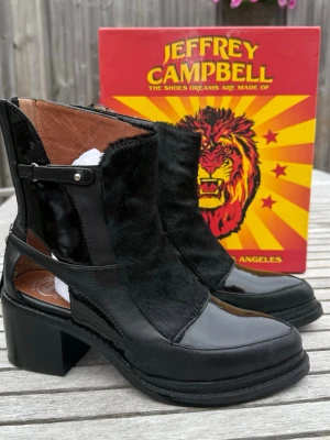 Svarta stövletter från Jeffrey Campbell (37) - Jeffrey Campbell ankle boots i svart läder med lackdetaljer och päls/hårskinn. Storlek 37. Mycket fint skick med minimalt använda sulor. Originalkartong medföljer. En ovanlig modell som är svår att hitta.