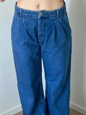 Stradivarius wide leg jeans mörkblå stl 42 - Mörkblå wide leg jeans fran Stradivarius i storlek 42. Hög midja med veck framtill, bred passform och bakficka. Använda men i fint skick.