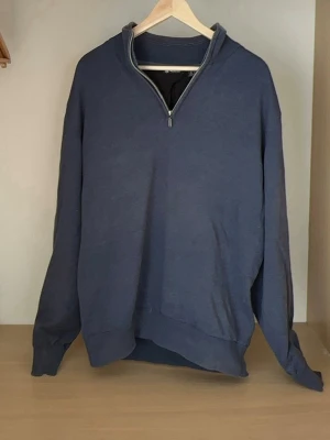 Mörkblå halvzip tröja från abacus - En stilren mörkblå tröja med halv dragkedja och hög krage. Tröjan har långa ärmar och ribbade muddar vid ärmslut och nederkant. Perfekt för lager på lager och enkel att matcha med olika outfits.