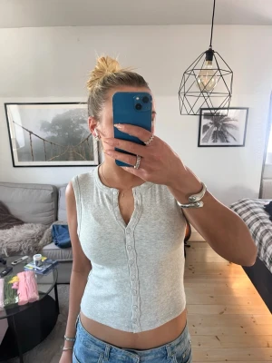 Ljusgrå ribbad linnetopp - Snygg ljusgrå ribbad linnetopp med rund hals och knappar hela vägen framtill. croppad modell 