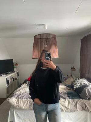 Svart hoodie med huva - En klassisk svart hoodie med huva. Hoodien har en avslappnad passform och ribbade muddar vid ärmslut och nederkant. 