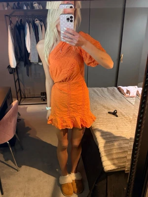 Orange one shoulder klänning - Snygg broderad orange kortklänning med oneshoulder och volangkant. 
