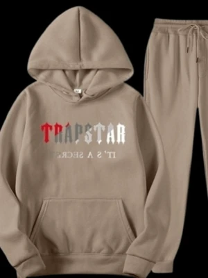 Trapstar loungewear set med hoodie - Säljer ett mjukt och bekvämt loungewear set från Trapstar med hoodie och matchande byxor. Finns i beige och svart. Hoodien har trycket 'TRAPSTAR IT'S A SECRET' i rött, grått och vitt framtill samt stor ficka och dragsko i huvan.