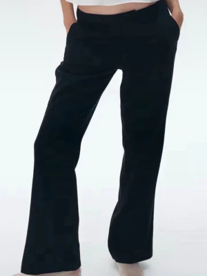 Svarta vida kostymbyxor-mid/low rise - Stilrena svarta kostymbyxor med rak och något vidare passform. Byxorna har fickor i sidorna, hällor för skärp och klassisk gylf med knapp och hake. Perfekta för en clean och modern look.