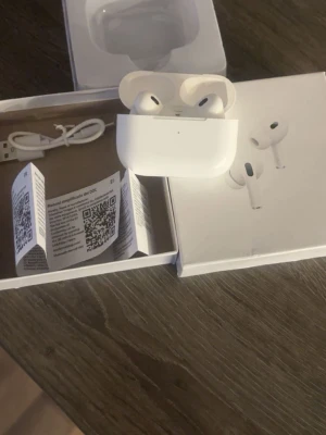 Airpods PRO  - Säljer ett par vita trådlösa hörlurar från Apple, modell AirPods Pro, med matchande laddningsetui. Hörlurarna har en stilren och kompakt design i blank plast. Laddningskabel och manual medföljer i originalförpackning. Har endast haft dessa i en månad, fick en nyare modell i födelsedag☺️