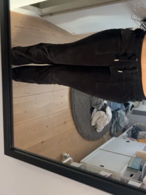 Svarta mjukisbyxor med raka ben - Säljer ett par svarta juicybyxor med raka ben oByxorna har fickor bax med knappdetaljer och är tillverkade i ett mjukt, bekvämt material som passar perfekt för chill dagar. Snygg och enkel design som funkar till det mesta. Byxorna är äkta. Byxorna har en liiiiten grön fläck på innerbenet men inget som syns