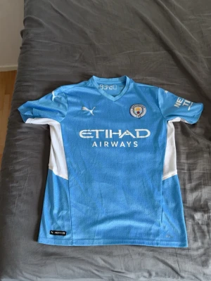 Puma - Snygg ljusblå Manchester City matchtröja från Puma med vita detaljer på sidorna och ärmarna. 22/23 hemmaställ.