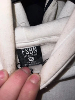 Vit hoodie från FSBN, relaxed fit XS - Säljer en vit hoodie från FSBN i relaxed fit, storlek XS. Hoodien har en klassisk huva och är tillverkad i ett mjukt material som passar perfekt för en chill och avslappnad stil. Enkel och clean design utan tryck.