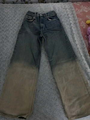 Wide leg jeans med dip dye-effekt - Snygga wide leg jeans med cool dip dye-effekt från mörkblått upptill till beige nedtill. Klassisk femficksmodell med hög midja och raka ben. Jeansen är i denim och har en trendig, avslappnad look som sticker ut.