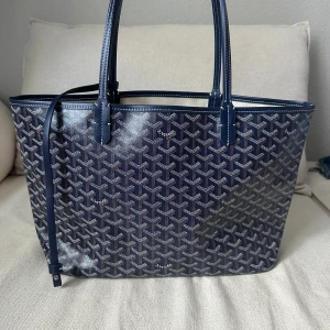 Mörkblå handväska - Elegant navy blue tote bag in the iconic inspired monogram pattern. A timeless and sophisticated everyday bag that fits all your essentials while staying lightweight and stylish. Perfect for work, travel, shopping, or daily use.  🔷 Classic navy monogram design 🔷 Spacious interior – fits laptop, books & daily essentials 🔷 Lightweight and comfortable to carry 🔷 Double top handles 🔷 Open top for easy access 🔷 Stylish and versatile – matches any outfit 🔷 Very good condition  Feel free to message me