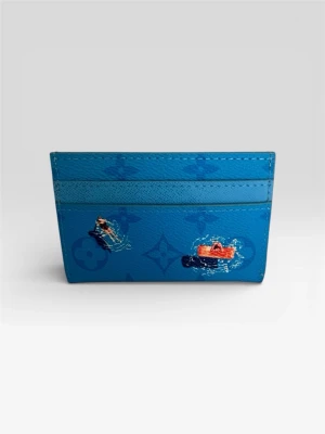 Blå korthållare - Snyggt blått kortfodral från Louise i präglat läder med ikoniskt monogrammönster. Dekorerad med färgglada illustrationer av båtar och vattensport, vilket ger en lekfull vibe. Perfekt för kort och småsaker, smidig att ha i fickan.