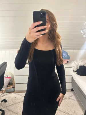 Svart långärmad långklänning - En stilren svart långklänning med lång ärm och fyrkantig urringning. Klänningen har en figurnära passform och är perfekt för dig som gillar en enkel men elegant look. Materialet känns mjukt och följsamt mot kroppen. I bra skick! 