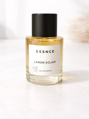 ESSNCE Lemon Eclair Eau de Parfum - Fräsch parfym från ESSNCE med doften Lemon Eclair. Flaskan är cylindrisk i genomskinligt glas med gul vätska och har en svart, matt kork. Stilig och enkel design med vit etikett framtill. Perfekt för dig som gillar citrusdofter. Helt oanvänd och aldrig provad 