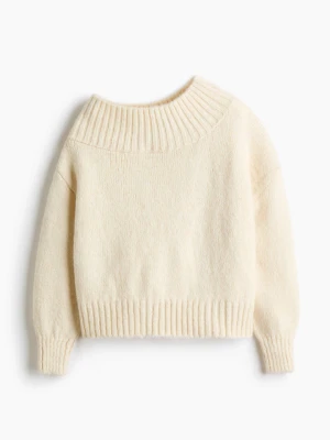 Krämvit off shoulder stickad tröja - Mysig krämvit stickad tröja med bred ribbad kant i halsen, perfekt för off shoulder-look. Tröjan har avslappnad passform, långa ärmar och ribbade muddar. Materialet ser mjukt och fluffigt ut, vilket gör den extra skön att bära.