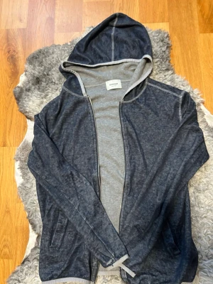 Mörkblå hoodie från Dondup - Snygg mörkblå hoodie från Dondup med dragkedja framtill och två fickor. Insidan är ljusgrå och materialet känns mjukt och bekvämt, perfekt för en avslappnad stil. Tillverkad i Italien och har en klassisk huva.