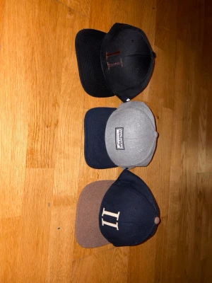 Tre Les Deux  - ‼️‼️ 199 Styck! Och 500 för alla 3 .‼️‼️Säljer tre snapback-keps från Les Deux . En svart med broderat II i guld, en grå med mörkblå skärm och Cayler & Sons-logga framtill, samt en mörkblå med brun skärm och vit II-brodyr. Klassisk form och justerbar baktill. 