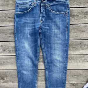 Dondup - Säljer ett par klassiska blå Dondup jeans. Jeansen har snygga slitningar och kontrastsömmar samt en patch med logga bak i midjan. Tillverkade i bomull för en skön och avslappnad look