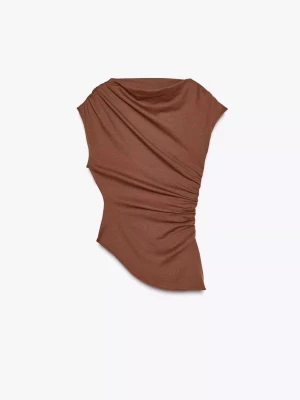 Brun asymmetrisk topp med rynk - Säljer en brun, asymmetrisk topp med rynkade detaljer på sidan. Toppen har en unik form med ena axeln bar och är tillverkad i mjukt material. Perfekt för dig som vill sticka ut med en cool och trendig look.