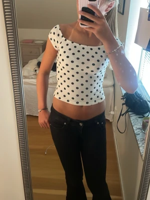 Vit prickig croppad topp new yorker - Säljer en vit croppad topp från FB Sister med svarta prickar. Toppen har korta ärmar och en figurnära passform som ger en trendig look. Perfekt för dig som gillar mönstrade toppar med lite retrovibbar.