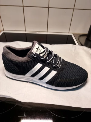 Adidas Los Angeles svarta sneakers 44.5 - Svarta Adidas Los Angeles sneakers med vita ränder och vit sula. Ovandelen är i meshmaterial. Helt oanvända!