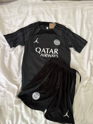 Svart PSG fotbollsställ Jordan - Psg fotbollsset i storlek S. Shortsen har fickor med dragkedjor. Helt nya och oanvända, perfekt till sommaren. Hör gärna av vid frågor!