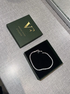 Silverarmband Viktor Frisk x Guldfynd - Snyggt silver armband från Viktor Frisk x Guldfynd. Armbandet har en tvinnad kedjedesign som ger en modern och stilren look. Perfekt accessoar för dig som gillar minimalistiska smycken med en exklusiv känsla. Längden är ungefär 19cm