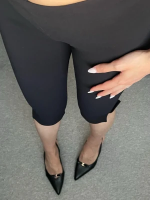 Capribyxor från stl S (med prislapp) - Svarta capribyxor från H&M Divided i stretchigt material. De säljs ej längre! Modellen är midjehög och slutar strax ovanför knäna. Perfekta för en elegant look. Har själv två par, ett i svart som på bilderna och ett i mörkblått. 