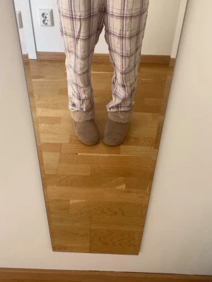 Rutiga pyjamasbyxor i beige och lila - Mysiga pyjamasbyxor med rutigt mönster i beige, vitt och lila. Byxorna har en avslappnad passform och är perfekta för hemmakvällar. Tillverkade i mjukt tyg som känns skönt mot huden. Perfekt för dig som vill ha det bekvämt och stilrent hemma.                                               de har några småfläckar och nopprar (bild 3), skriv för mer bilder❤️ man kan vika ner i midjan för att få de mer lågmidjade, se bild 2!!❤️ byxorna har kanter längst ner på benen.