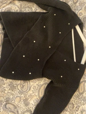 Svart stickad tröja med pärlor - Mysig svart stickad tröja med dekorativa vita pärlor.  Tröjan har en ribbstickad struktur och långa ärmar. Perfekt för dig som vill ha en enkel men ändå unik look. Den är i storlek xs men den är stor i storlek så skulle tippa på stolek s. Perfekt nu till sena sommarkvällar eller till hösten. Djur finns i hemmet, allt tvättas innan leverans.💞