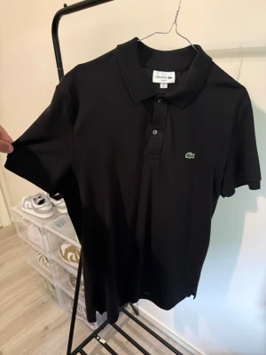 Svart pikétröja från Lacoste - Originell Lacoste piké Slim fit, Strl M. Köptes Maj detta året på Hede Fashion i Göteborg.  Hunnit använda 2-3 gånger endast… Säljes då den är för stor på mig. Strl M, Slim/muscle-fit