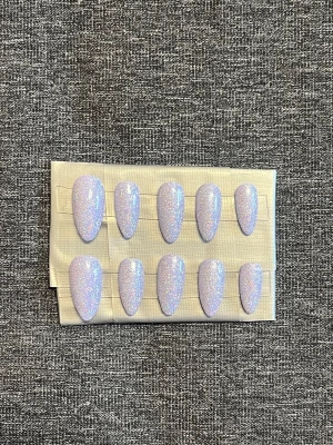 Press-on naglar || Storlek M - Snygga press-on naglar i en lila nyans med massor av glittereffekt. Naglarna har en spetsig almondform och ger en trendig look. Perfekta för dig som vill ha glam på nolltid! Storlek M, Det du får med dig : * Fil och manikyr pinne * nagellim klistermärken * 2 lappar av rengöring för naglar.