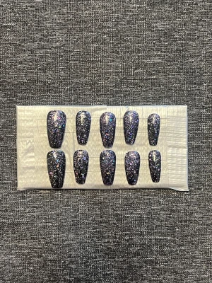 Press-on naglar || Storlek M - Snygga press-on naglar i svart med massor av glitter i olika färger. Naglarna har en något avlång, fyrkantig form och ger en riktigt glam känsla. Perfekta för dig som vill ha en statement-look på nolltid. Storlek M, Det du får med dig : * Fil och manikyr pinne * nagellim klistermärken * 2 lappar av rengöring för naglar.