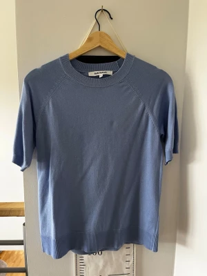 Ljusblå topp från Soft Rebels - Supersnygg ljusblå topp från Soft Rebels med korta ärmar och rund hals. Toppen har ribbade detaljer vid halsringning, ärmslut och nederkant. Perfekt att styla med jeans eller kjol för en clean look. Använd fåtal gånger