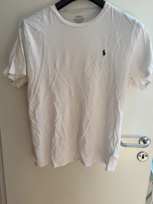 Ralph Lauren T-Shirt - Vit T-Shirt från Polo Ralph Lauren. Köpt från Kids Brand Store, därav storleksmarkeringen 18-20 år (XL). Jag skulle säga att den motsvarar S/M i herrstorlek.