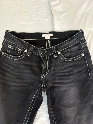 Svarta jeans med vita sömmar - Snygga svarta jeans från Gina Tricot med kontrasterande vita sömmar och klassisk femficksmodell. Jeansen har låg midja och lätt utsvängda ben, vilket ger en trendig siluett. Perfekta för dig som vill sticka ut med detaljer!