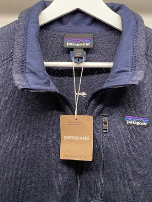 Mörkblå fleeceväst från Patagonia - Snygg mörkblå fleeceväst från Patagonia med hel dragkedja och bröstficka med zip. Klassisk ståkrage och broderad logga på bröstet. Perfekt lager-på-lager-plagg för kyliga dagar.