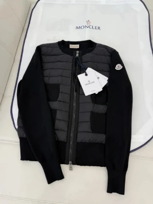 Svart cardiganjacka  - Snygg svart cardiganjacka f med quiltad front och stickade ärmar. Jackan har dragkedja framtill, två fickor. Perfekt för lager-på-lager och stilren look.