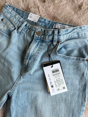 Ljusblå raka jeans från Vero Moda, helt oanvända  - Snygga ljusblå jeans från Vero Moda med rak passform och klassisk femficksdesign. Jeansen har hög midja, bälteshällor och detaljer i silver. Tillverkade i bomullsdenim för en skön och avslappnad look.