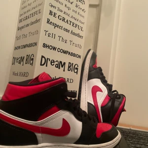 Nike Air Jordans svart, röd och vit - Säljer ett par klassiska Nike Air Jordans med svart, röd och vit färgkombination. Skorna har högt skaft, snörning och den ikoniska swoosh-loggan i rött på sidan. Perfekta för dig som gillar streetwear och sneakers med attityd. Använda ett par gånger,