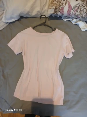 Ljusrosa t-shirt från 157 - Snygg ljusrosa t-shirt från 157 i 100% bomull. Modellen är klassisk med rund halsringning och korta ärmar. Perfekt att matcha med jeans eller kjol för en enkel och fräsch look.