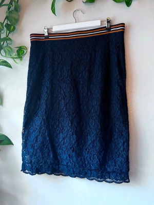 Tjusig pennkjol i spets  - Vacker marinblå knäkjol i spets från Holly & Whyte från Lindex Resår i midjan som är orange, marinblå och vit Dragkedja och slits i bak  Använd ett fåtal gånger, mycket bra skick  Mått:  Midja: 45,5cm rakt över Längd: 69cm  Se även andra annonser för bundle! 🌷  Avhämtning i Gävle/Uppsala går att lösa (skriv pm innan köp)