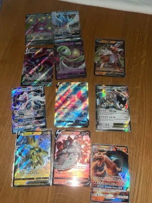Samling Pokémonkort GX, EX & V - Säljer en samling med 11 Pokémonkort av typen GX, EX och V. Korten är holografiska och har färgstarka motiv med olika Pokémon som Charizard, Zeraora, Primarina och fler. Alla kort är officiella från Pokémon och har klassisk blå baksida. Perfekt för samlare eller dig som vill boosta din lek.  TITTA ALL BILDER HAR ÄVEN LITE VANLIGARE KORT !