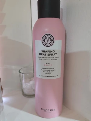 Maria Nila Shaping Heat Spray - Shaping Heat Spray från Maria Nila är en värmeskyddande spray i en rosa flaska. Ger stadga och skyddar håret vid styling med värmeverktyg. 100% vegansk och tillverkad i Sverige. Innehåller 250 ml. Flaskan väger 193 g (ca 85 % kvar av innehållet). Suveränt värmeskydd som doftar magiskt. Säljes då jag har för mycket hårprodukter.