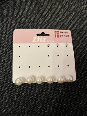 Pärlörhängen från Ztiz - Säljer ett set med klassiska pärlörhängen från Ztiz. Örhängena är vita och runda med en glansig yta som ger en stilren look. Perfekta för att lyfta vilken outfit som helst. Kommer på originalkortet.