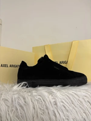 Svarta sneakers från Axel Arigato - Stilrena svarta sneakers från Axel Arigato i mocka med ton-i-ton snörning och diskret logga på sidan. Skorna har en chunky sula och en klassisk låg profil som passar till många olika outfits.