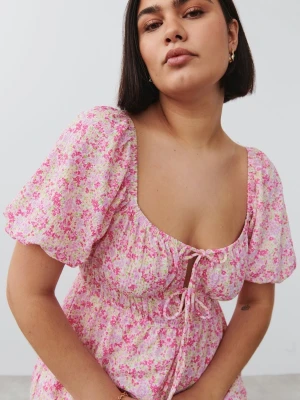 Blommig klänning GinaTricot - Superfin kort klänning med rosa och vita blommor, puffärmar och söt knytning framtill från GinaTricot. Klänningen har en luftig passform och är perfekt för varma dagar. Tillverkad i mjuk bomull som känns skön mot huden.