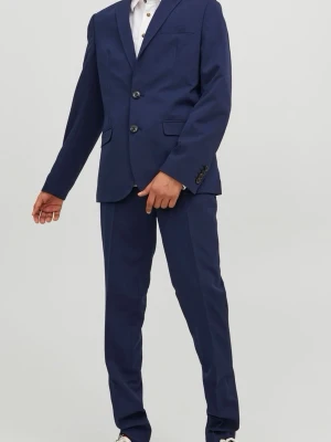 Marinblå kostym från Jack and Jones - Snygg marinblå kostym från Jack and Jones med tvåknäppt kavaj och matchande byxor. Klassisk passform med fickor fram och knappar vid ärmslut. Tillhörande vit skjorta. Kostymen är storlek 158, skjortan 152. Sonen var 165 cm lång när han hade den. Superfin och använd en gång på ett bröllop så i toppskick. 