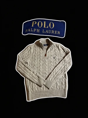 Grå kabelstickad Tröja Polo Ralph Lauren - Kabelstickad Grå Quarterzip från Polo Ralph Lauren med halv dragkedja och ribbade muddar. Tröjan har lång ärm och den klassiska broderade Polo Ralph Lauren loggan på bröstet. Info: Tröjan är i storlek M och helt utan defekter. Mått: Längd: 67cm | Bröstvidd: 47cm | Hör av dig vid minsta fundering⭐️Kan gå ner i pris vid snabb affär🤝